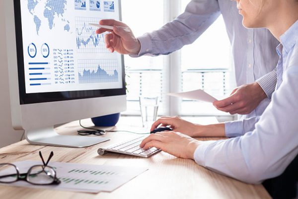 people reviewing desktop computer screen displaying charts and graphs
