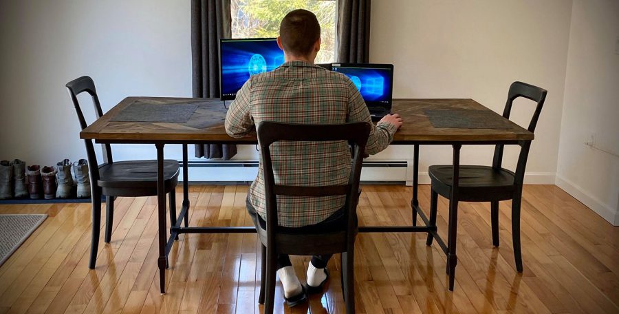 Back of man using computer while sitting at dining table